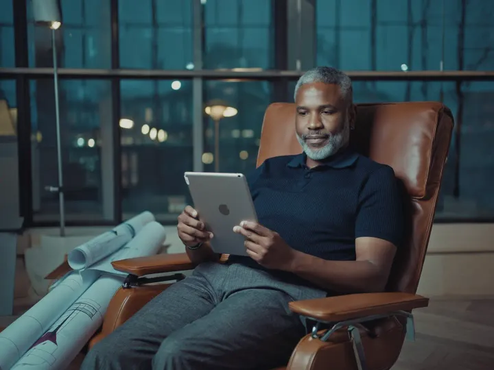 A marketing vice president reviews a tablet from a leather lounge chair