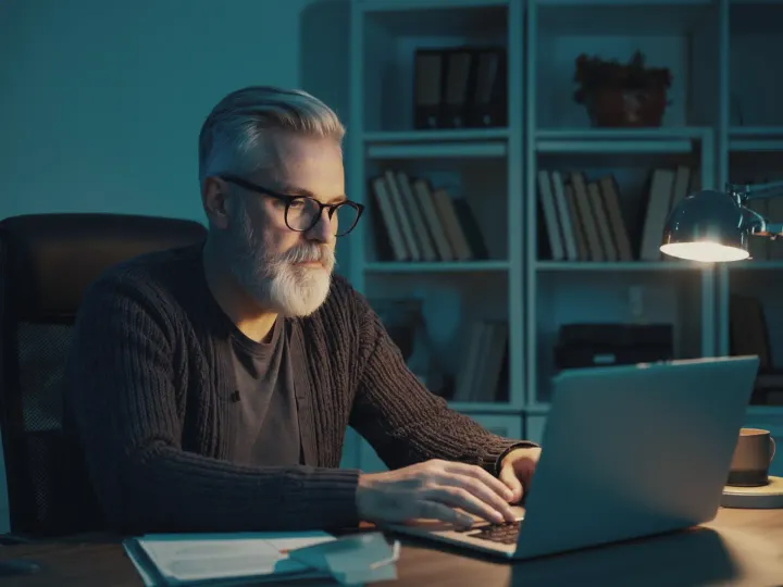 A communications vice president works on a laptop in a study at night